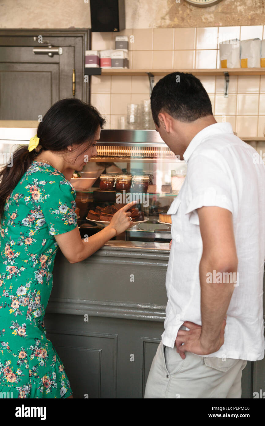 Giovane donna mostra il marito dolci sulla vetrina Foto Stock