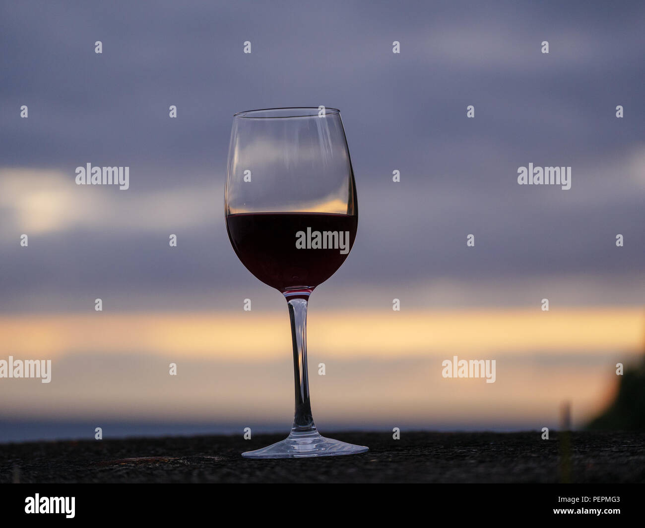 Bottiglia di vino e glas con il cielo al tramonto e il mare in background Foto Stock