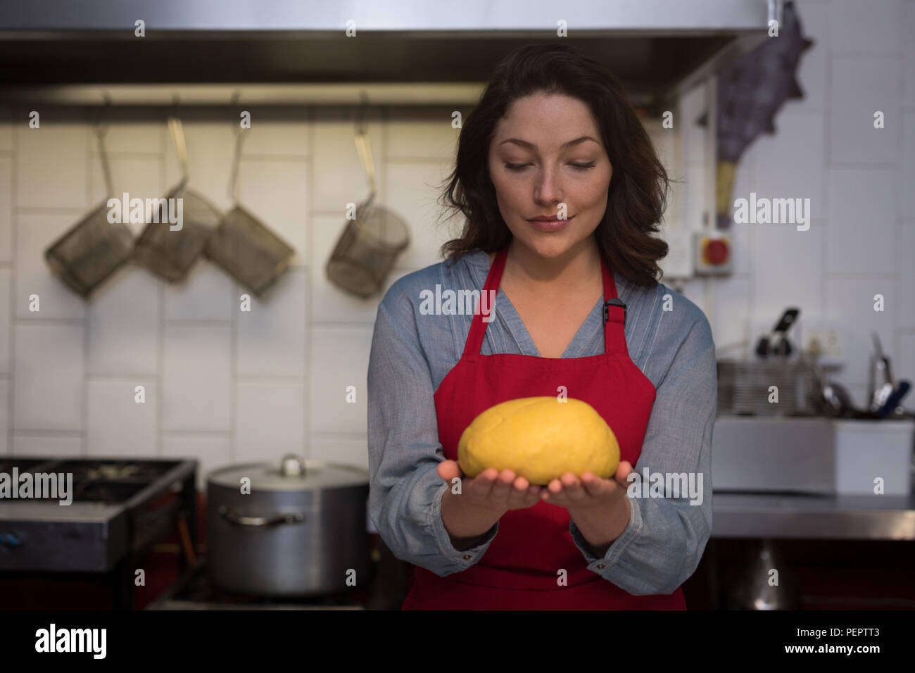 Il panettiere di sesso femminile in possesso di una prova di impasto a mano Foto Stock