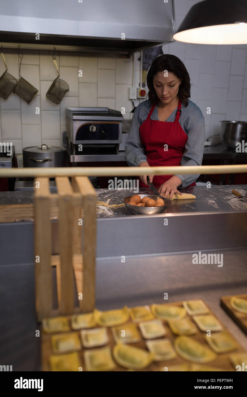 Il panettiere femmina pasta da taglio durante la preparazione per la pasta Foto Stock