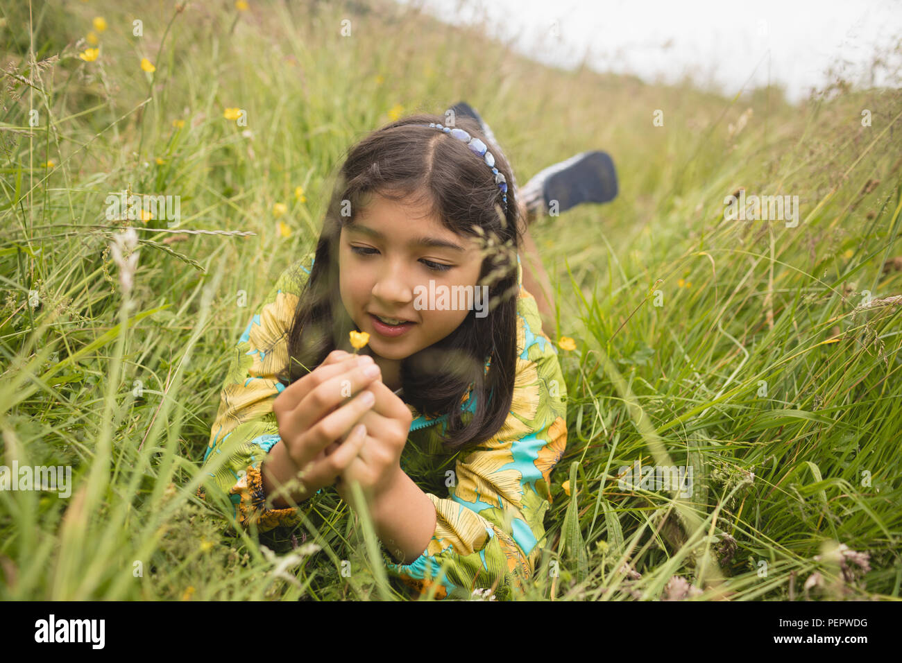 Ragazza con fiore sdraiati sull'erba verde Foto Stock