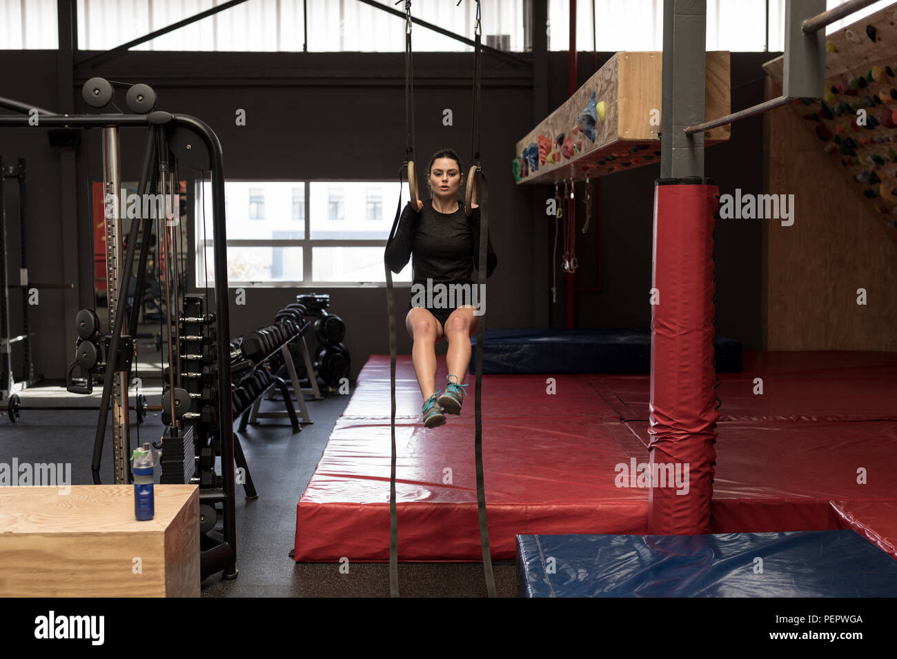 Donna facendo tirare ups su anelli di ginnastica in palestra per il fitness Foto Stock