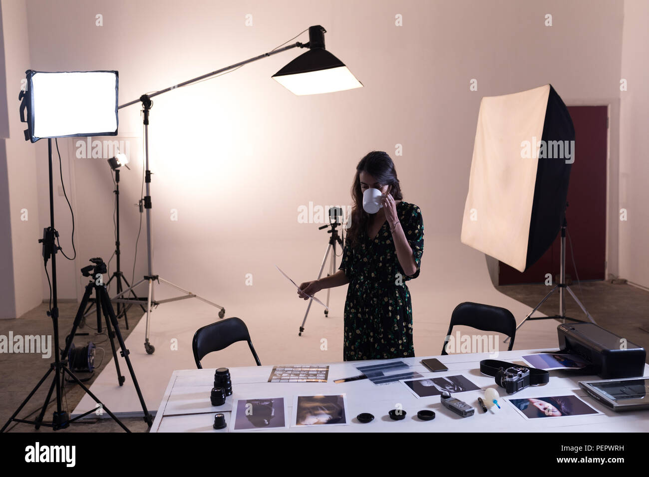 Fotografo femmina avente il caffè mentre guardando le fotografie Foto Stock