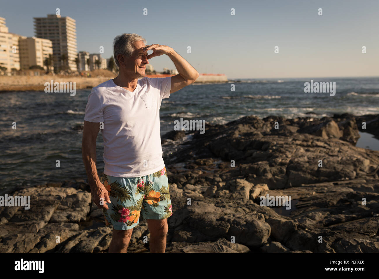 Senior uomo in piedi sulla roccia vicino al mare Foto Stock