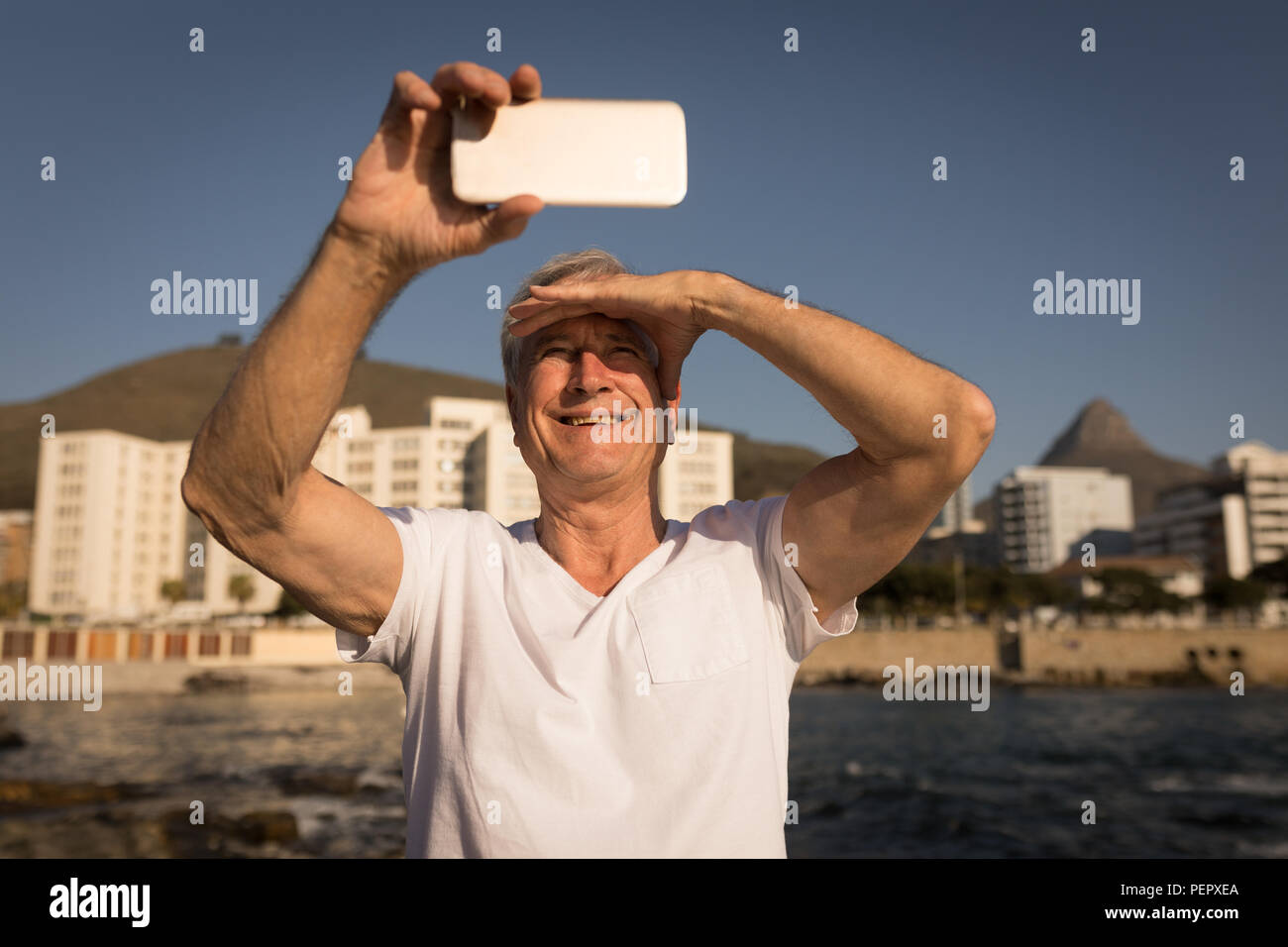 Senior uomo prendendo selfie vicino a lato mare Foto Stock