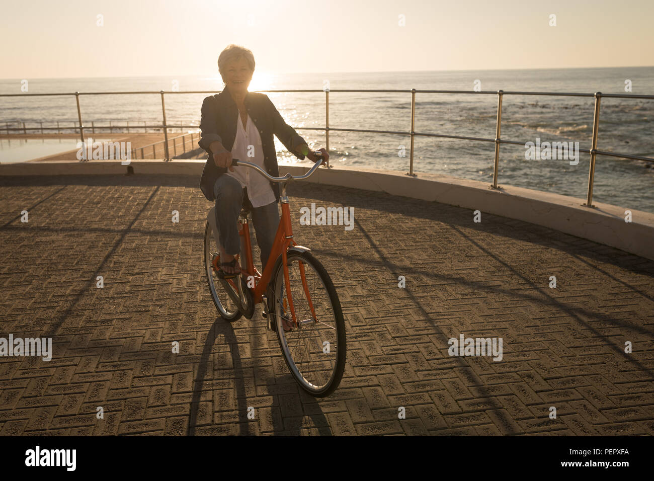 Senior donna Bicicletta Equitazione presso il lungomare Foto Stock