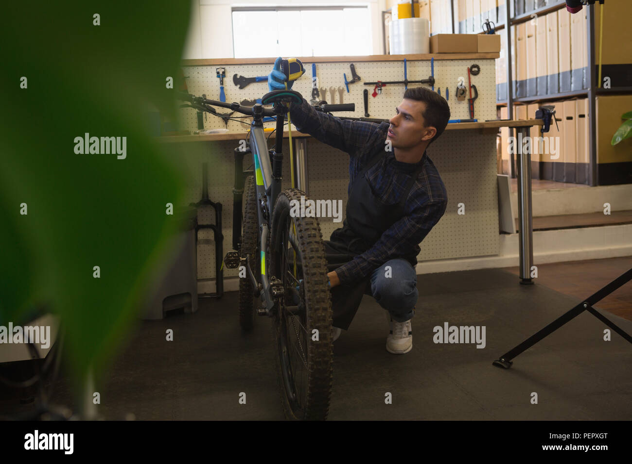 L uomo per misurare la lunghezza della sella per bicicletta in officina Foto Stock