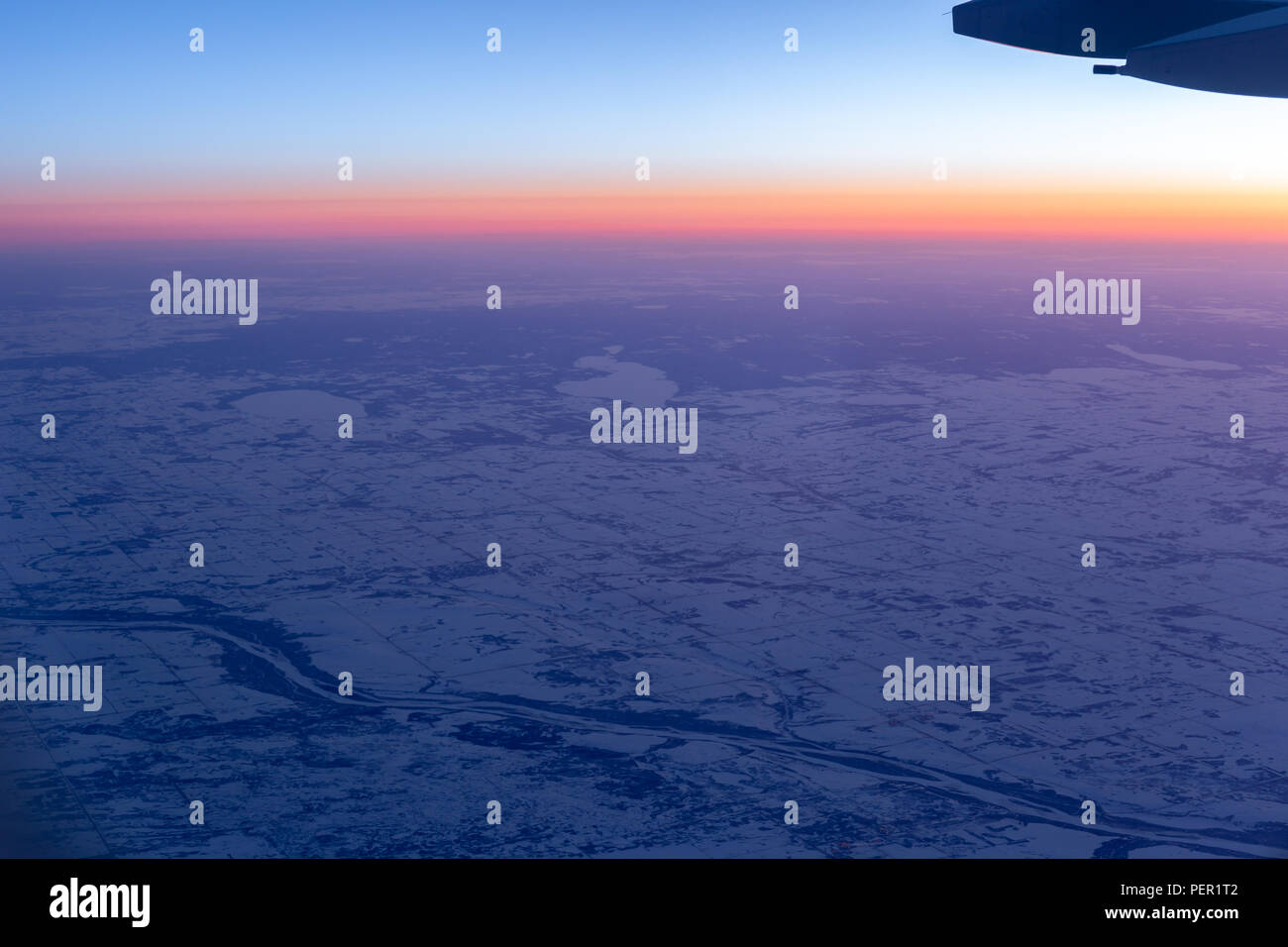 Vista aerea da aereo finestra sopra la terra con la neve e il bellissimo tramonto. Foto Stock