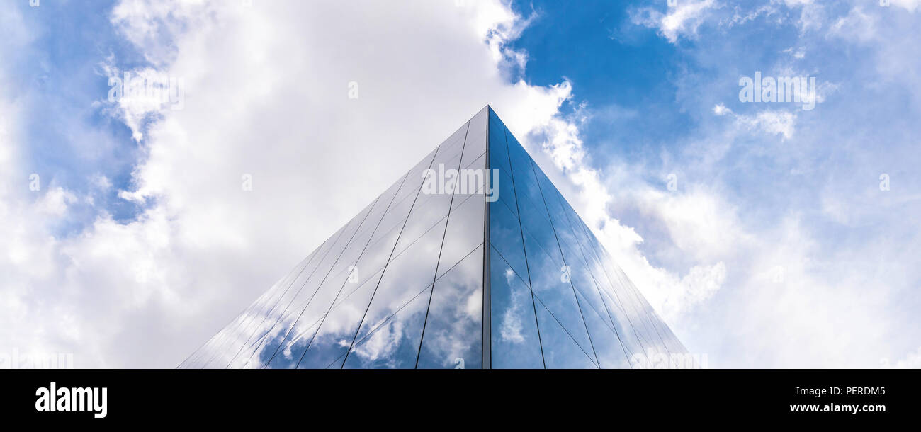 Drammatico il cielo blu con nuvole bianche riflessione sull'architettura moderna edificio in vetro Foto Stock