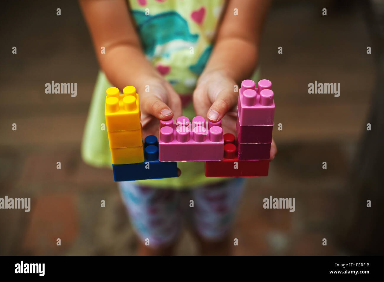 Un bambino piccolo è azienda giocattoli colorati, che mostra la creatività. Foto Stock