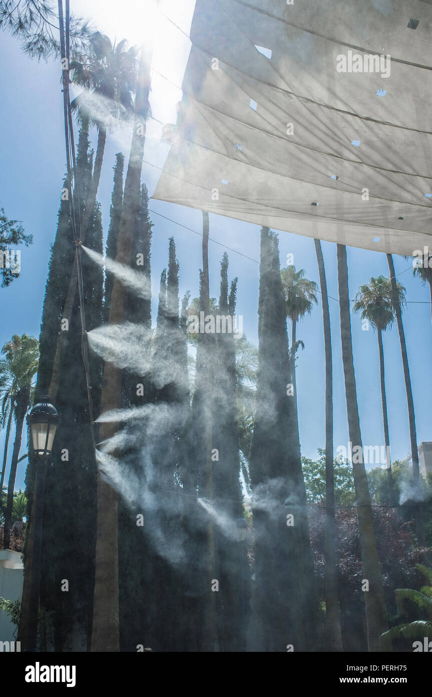 Tenda gli sprinkler e gli spruzzi di acqua nebulizzata a parco pubblico. Dispositivi per il raffreddamento della calda estate la temperatura in Spagna all'aperto Foto Stock