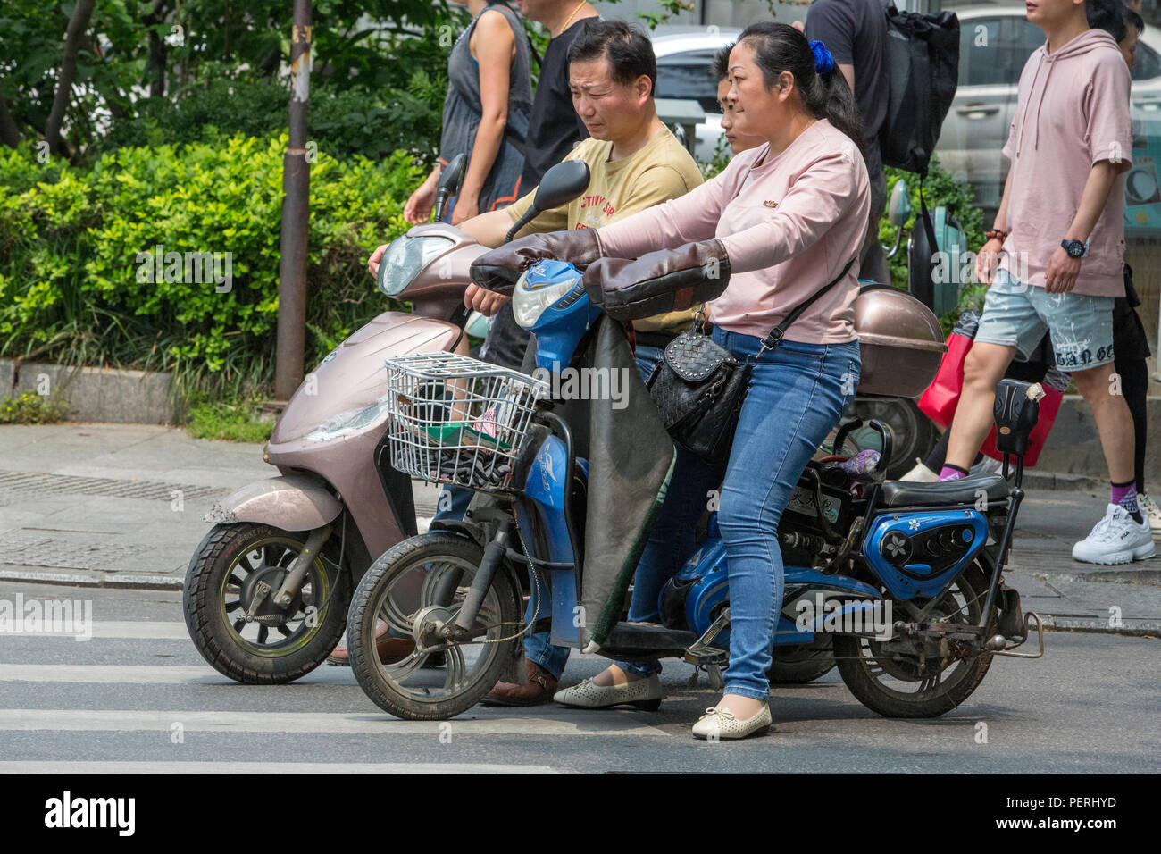 Suzhou, Jiangsu, Cina. Il cinese con moto elettrico. Foto Stock