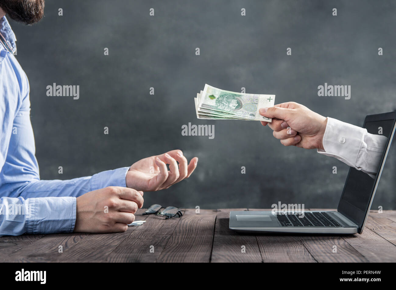 Imprenditore ottiene il polacco contanti dal lato in uscita del monitor di un laptop. La concezione di guadagnare denaro su internet Foto Stock