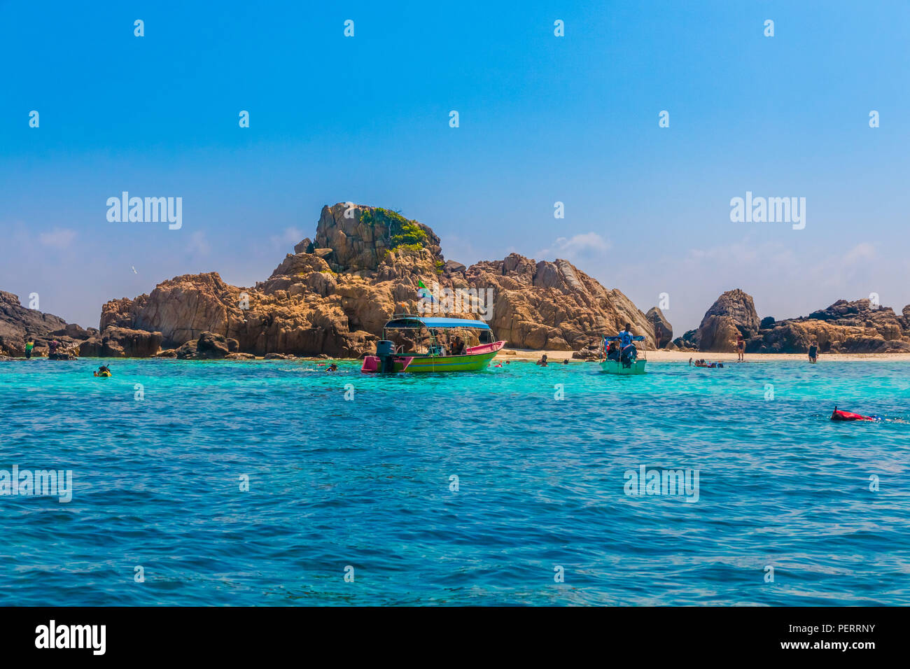 Ottima vista di Tokong Burung (Isola degli uccelli), un'isola disabitata nei pressi di Perhentian Kecil in Malaysia. Barche a motore sono di ancoraggio ed i turisti sono... Foto Stock