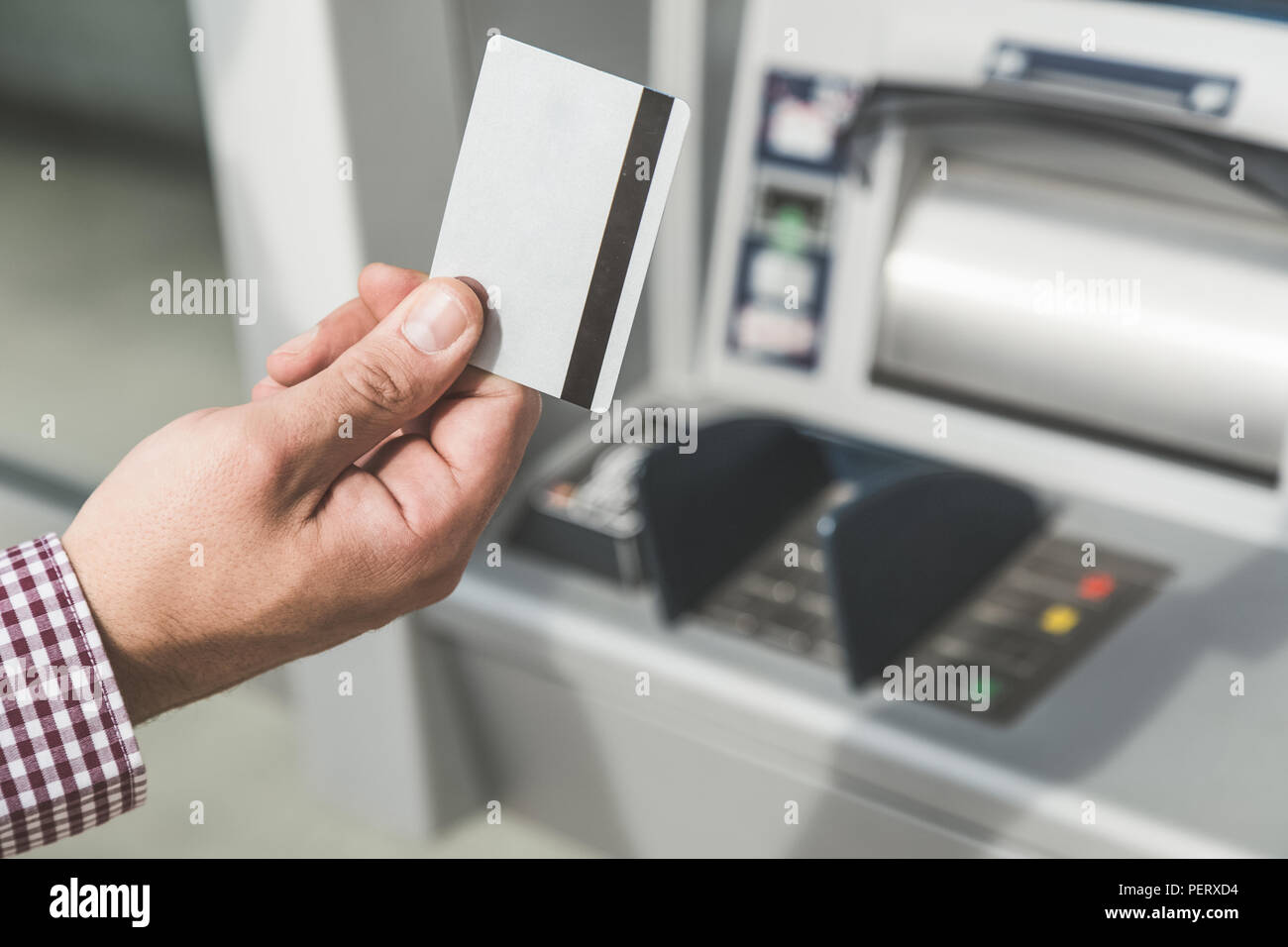 Close up man mano azienda carta di credito accanto all'atm. Foto Stock