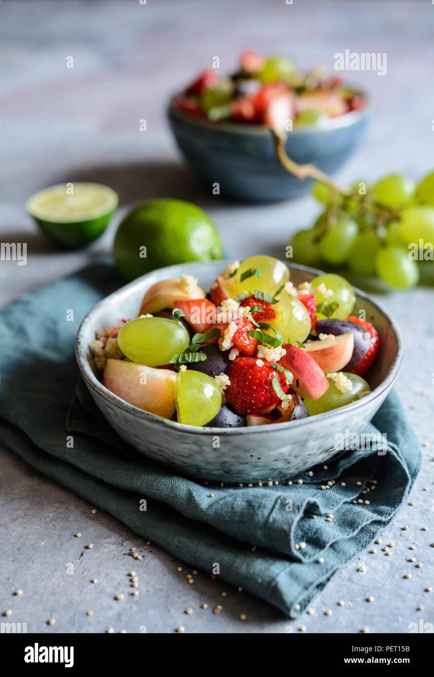 Una sana insalata di frutta con la quinoa, fragola, pesca, uva bianca, prugne, menta e miele medicazione di lime Foto Stock