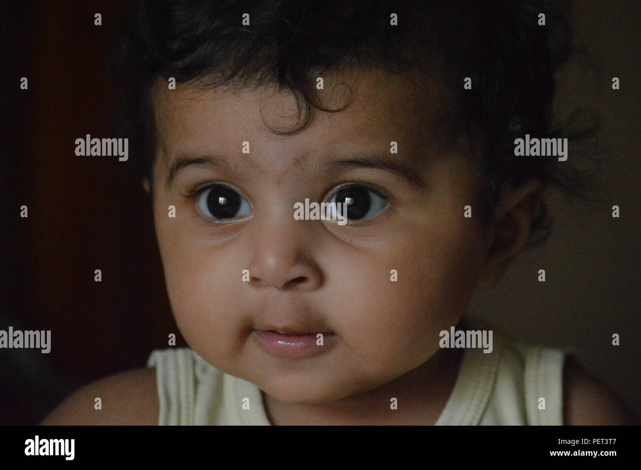 Infantile close up sono adorabili e molto espressiva big eyed carino Indian's delizioso di fronte a un vero e proprio tesoro e il piacere di guardare a. Foto Stock