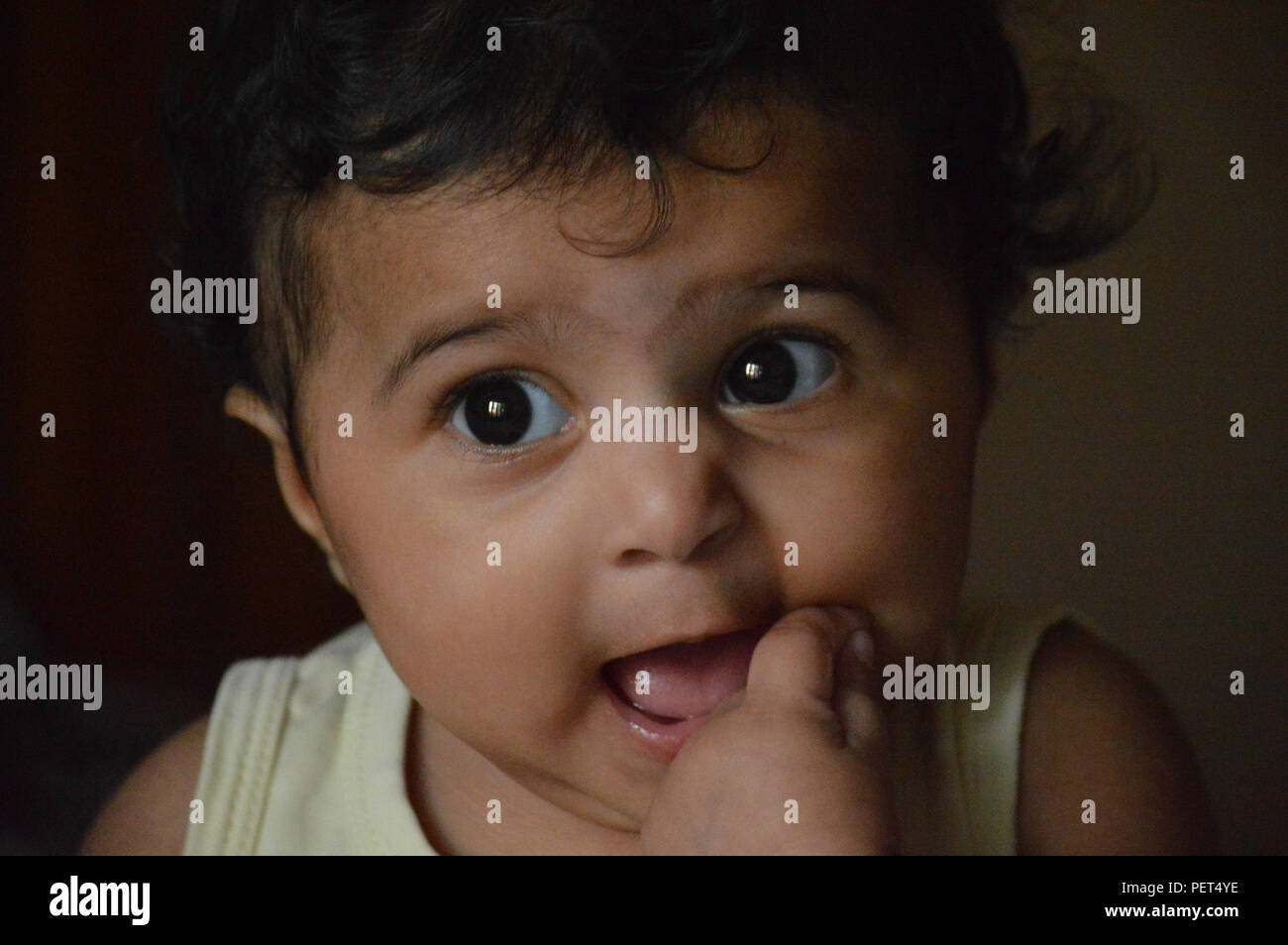 Infantile close up sono adorabili e molto espressiva big eyed carino Indian's delizioso di fronte a un vero e proprio tesoro e il piacere di guardare a. Foto Stock
