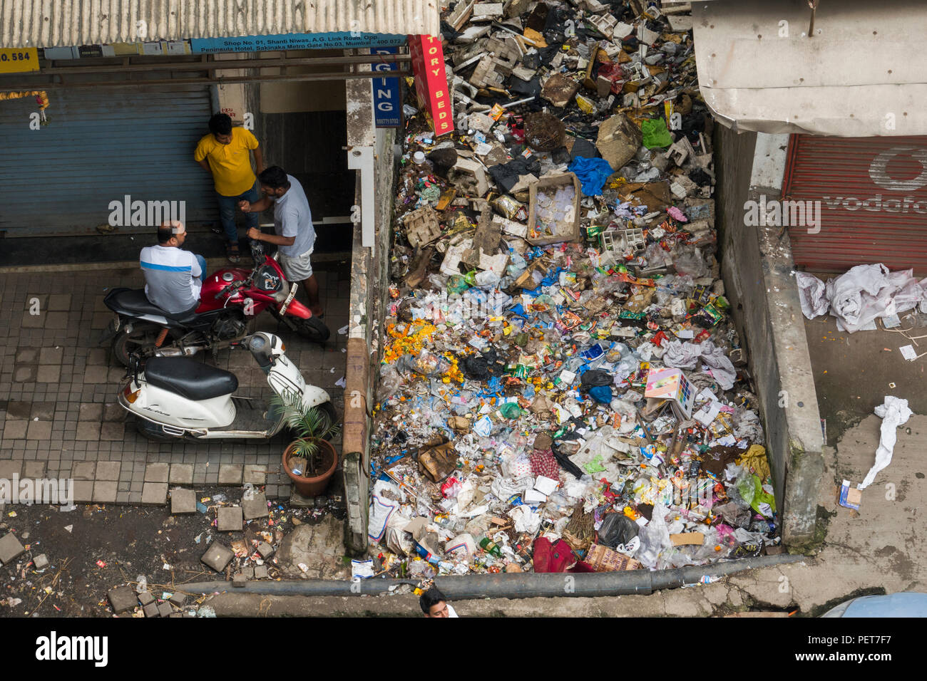 Gran mucchio di immondizia di plastica e di altri rifiuti seduti tra gli edifici commerciali in Asalpha, Mumbai, India Foto Stock