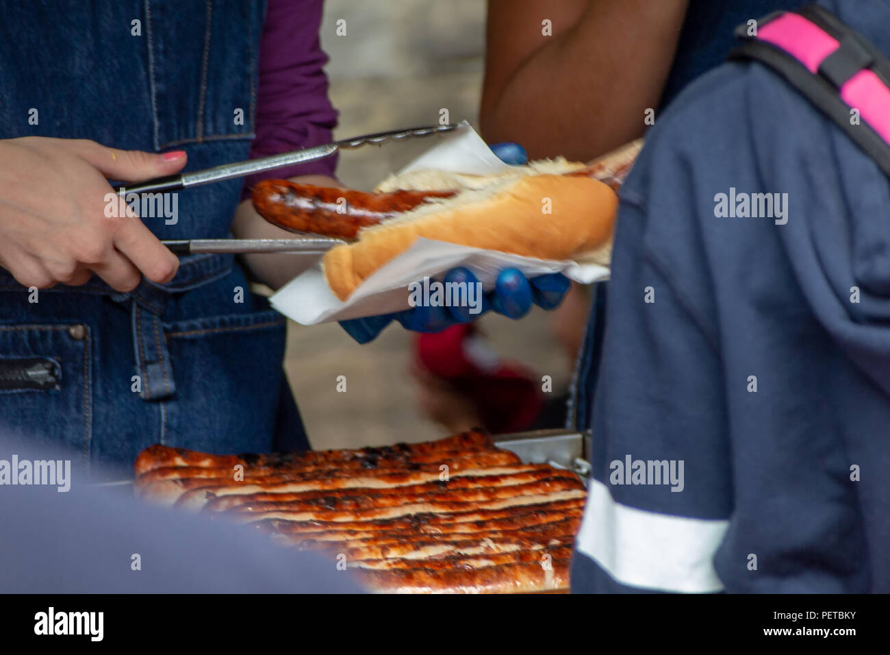 Un venditore si prepara un tedesco di Hot Dog per un cliente nel mercato di Borough, Southwark, Londra UK Foto Stock