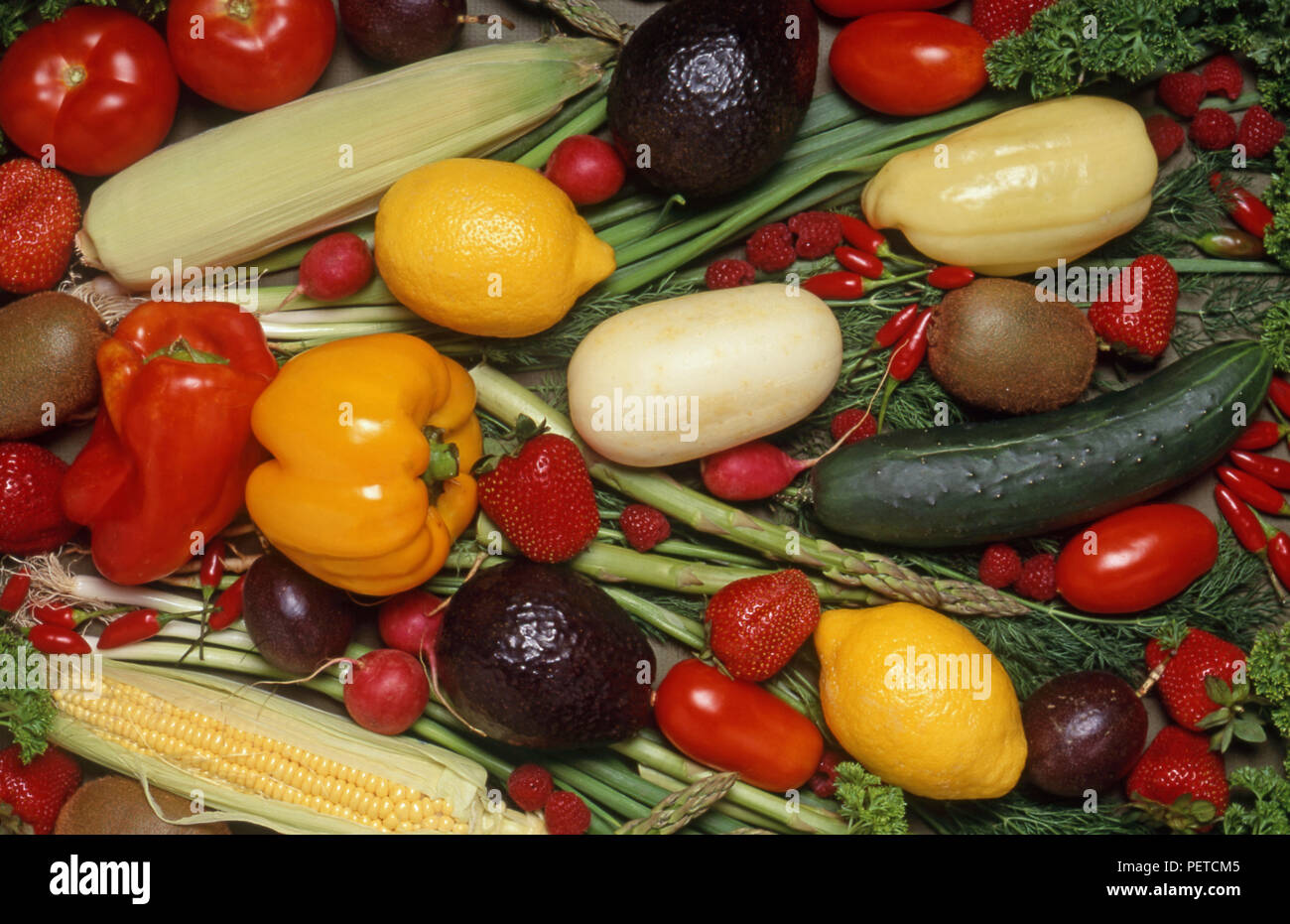 Disposizione mista di verdure fresche e frutta compresi peperoni, cetrioli, limoni, pomodori, mais, fragole, lamponi e avocado. Foto Stock