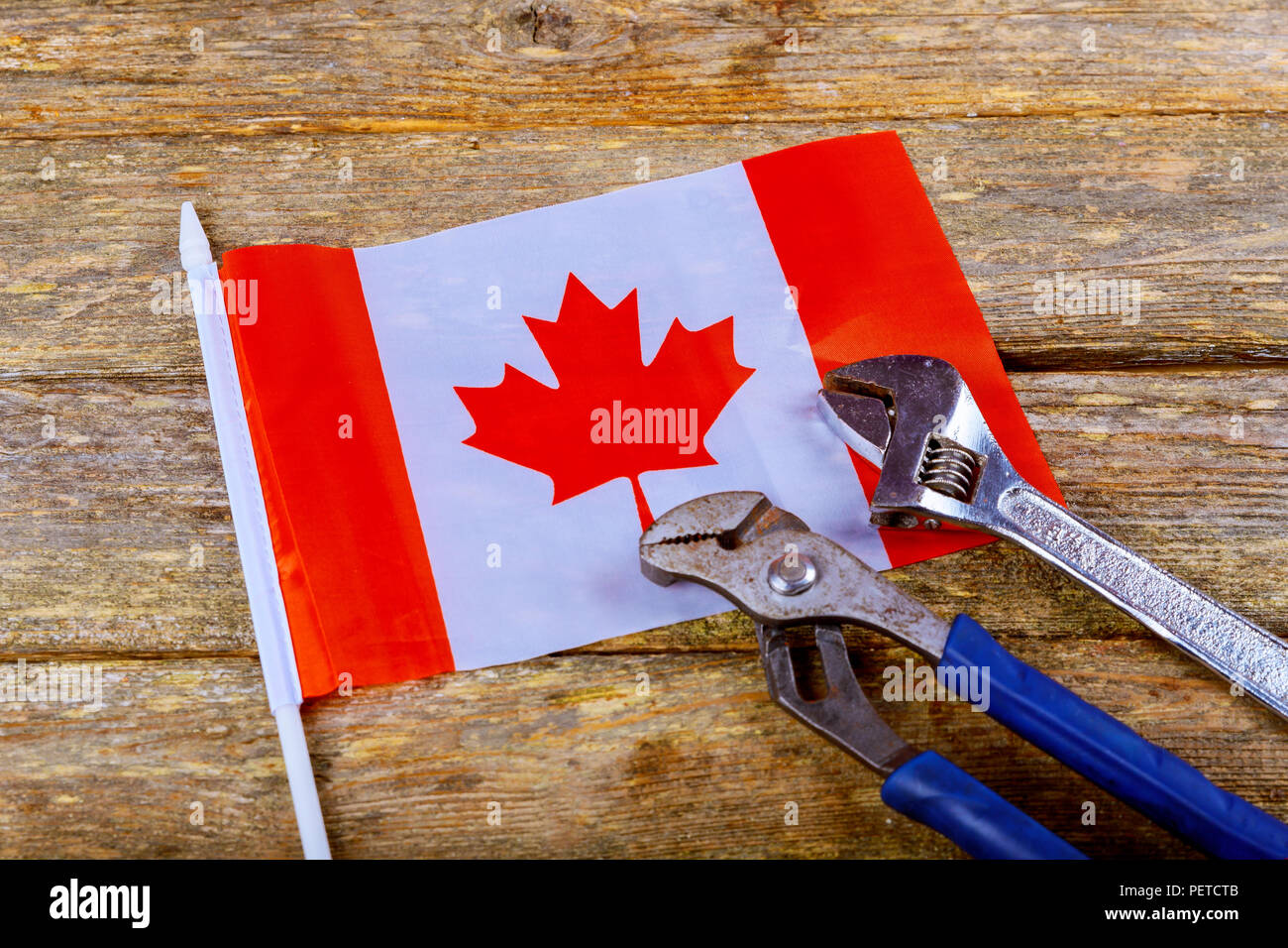 Bandiera canadese giornata di lavoro chiave costruttore ingegnere strumenti su un denim lavoratori, costruttore di strumenti di sfondo di legno Foto Stock