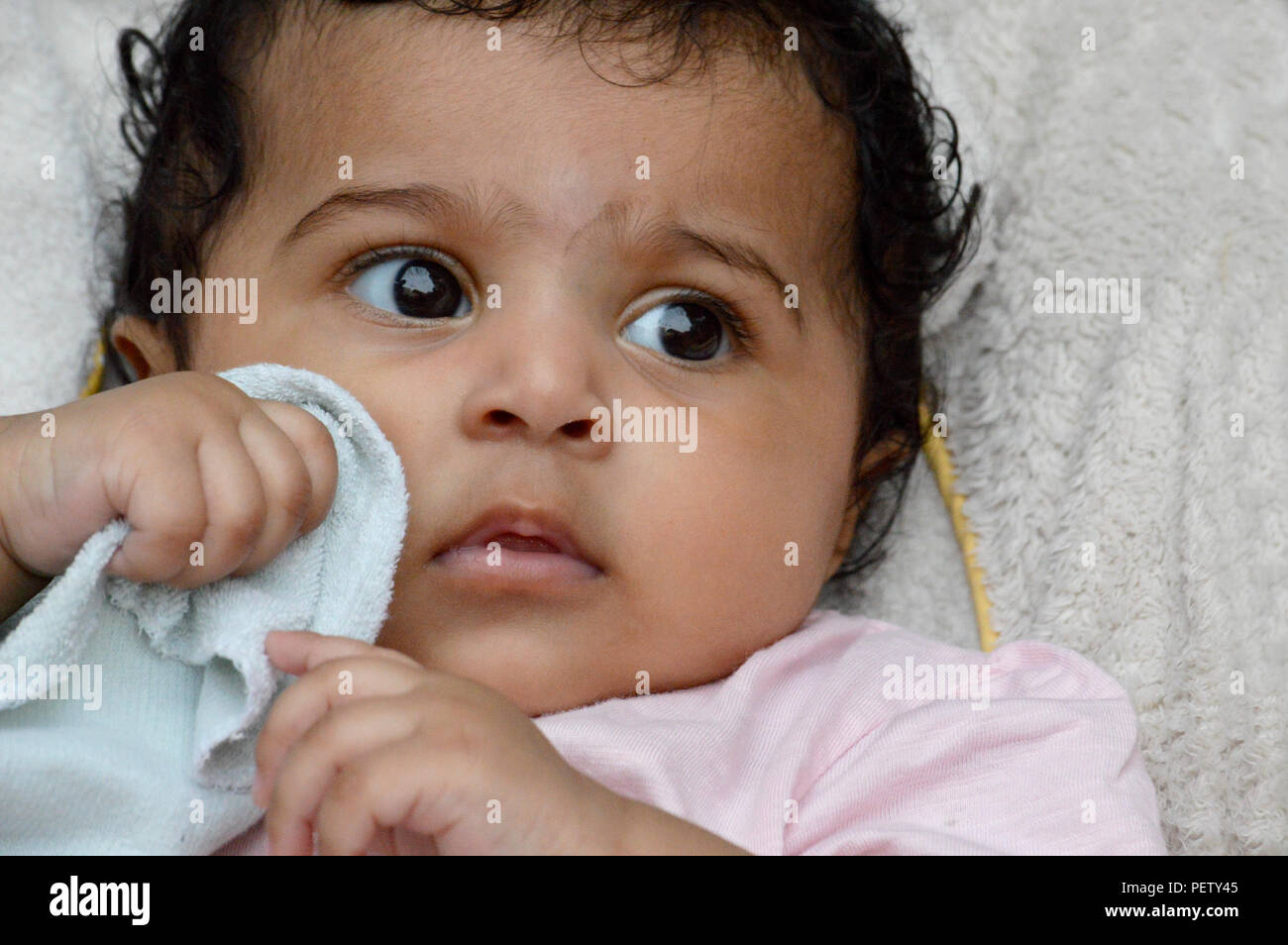 Infantile close up sono adorabili e molto espressiva big eyed carino Indian's delizioso di fronte a un vero e proprio tesoro e il piacere di guardare a. Foto Stock