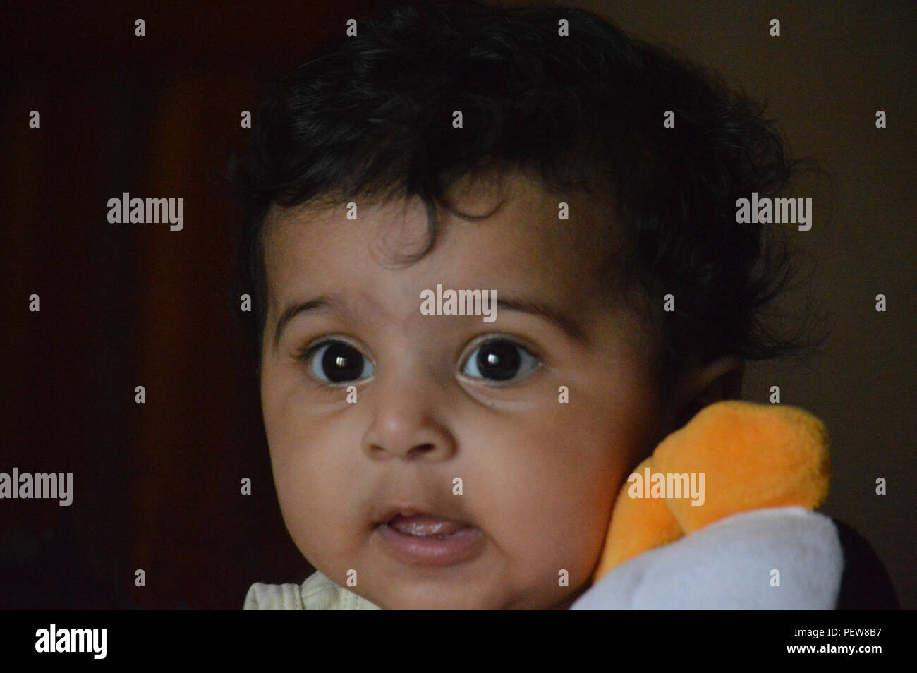 Infantile close up sono adorabili e molto espressiva big eyed carino Indian's delizioso di fronte a un vero e proprio tesoro e il piacere di guardare a. Foto Stock