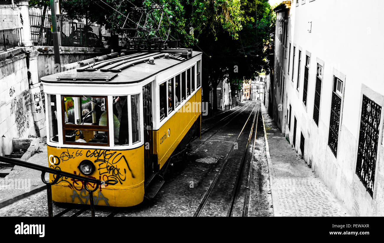 Vista del paesaggio di un vecchio tram giallo salendo la collina per raggiungere il Bairro Alto, girato a Lisbona, Portogallo Foto Stock