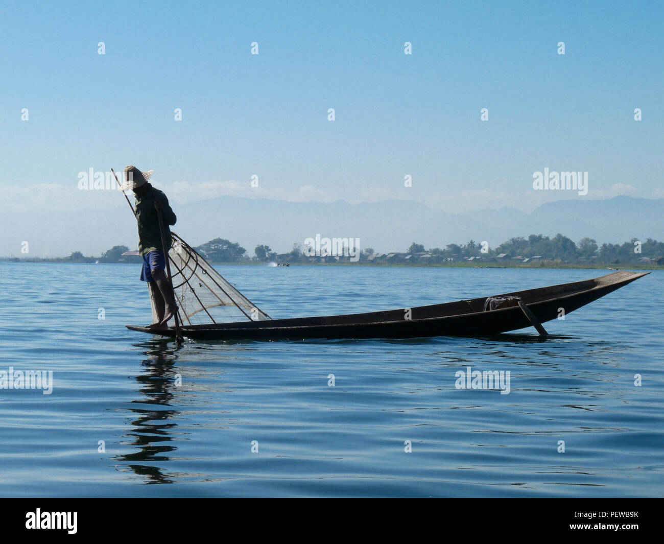 Vista del paesaggio di un pescatore sul Lago Inle in colline Shan, Myanmar, pesca con una gamba bilancia tecnica, con il cielo azzurro in background Foto Stock