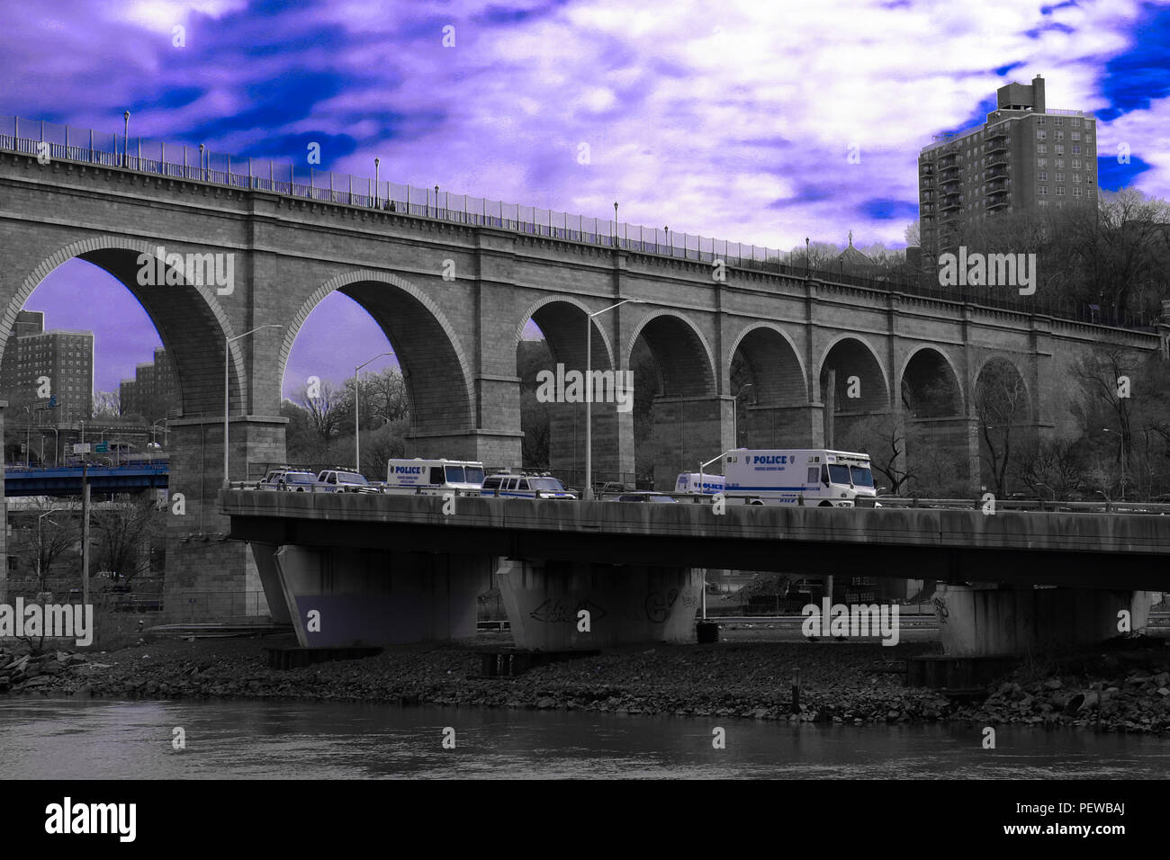 Vista del paesaggio dell'Alto Ponte, il ponte più antico di New York, con blu cielo nuvoloso in background e diversi veicoli NYPD nella parte anteriore Foto Stock