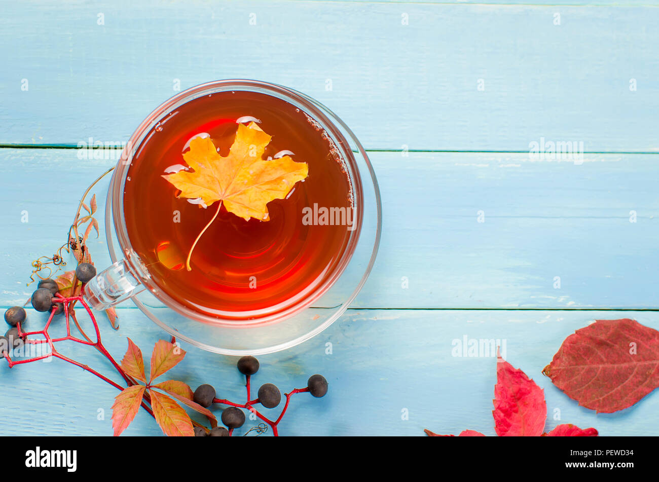 Autunno ancora in vita. Tazza di tè, foglie sul blu sullo sfondo di legno, vista dall'alto. Foto Stock