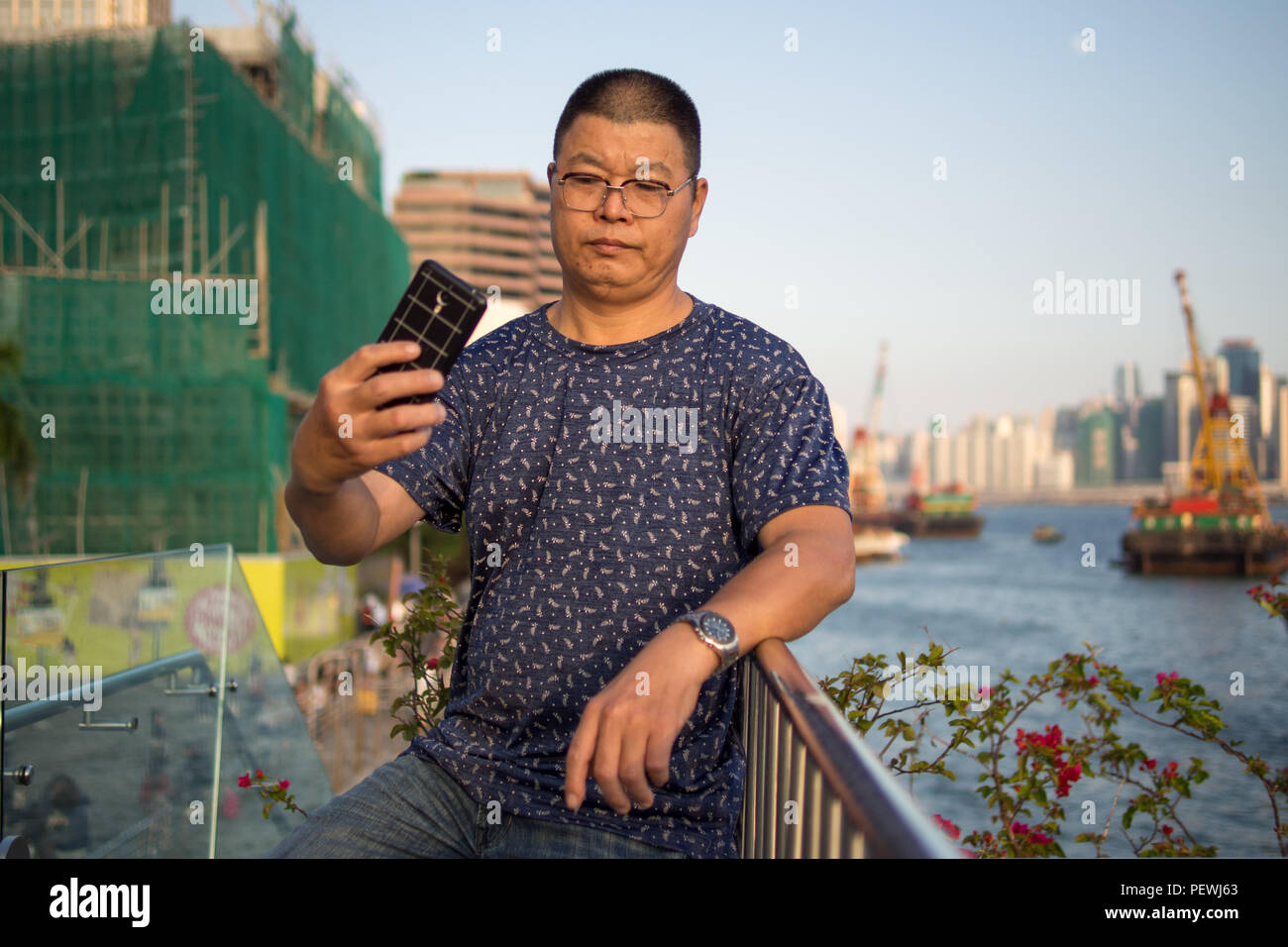 Un continente turistico cinese prende un selfie presso il Victoria Harbour, Tsim Sha Tsui Hong Kong. Foto Stock
