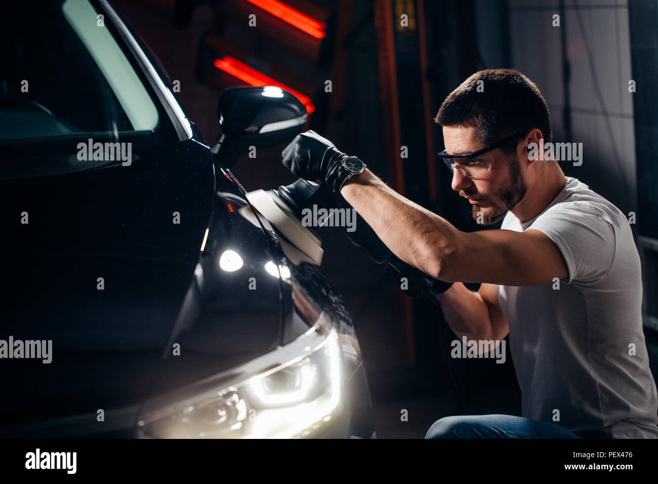 Dettagli auto - mani con lucidatrice orbitale nel negozio di riparazioni auto. Messa a fuoco selettiva. Foto Stock