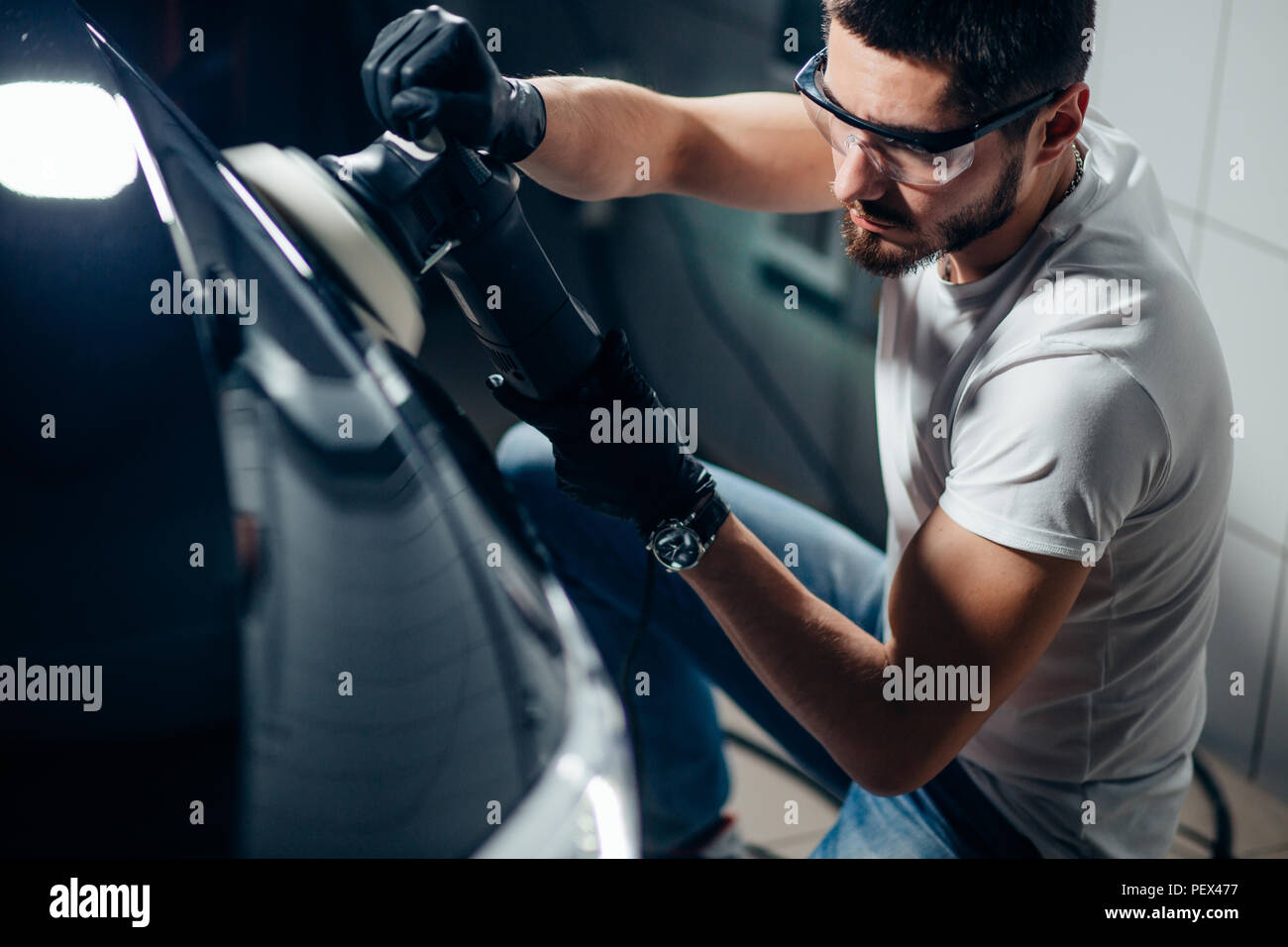 Dettagli auto - mani con lucidatrice orbitale nel negozio di riparazioni auto. Messa a fuoco selettiva. Foto Stock
