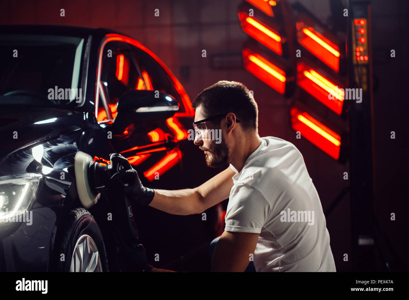 Dettagli auto - mani con lucidatrice orbitale nel negozio di riparazioni auto. Messa a fuoco selettiva. Foto Stock