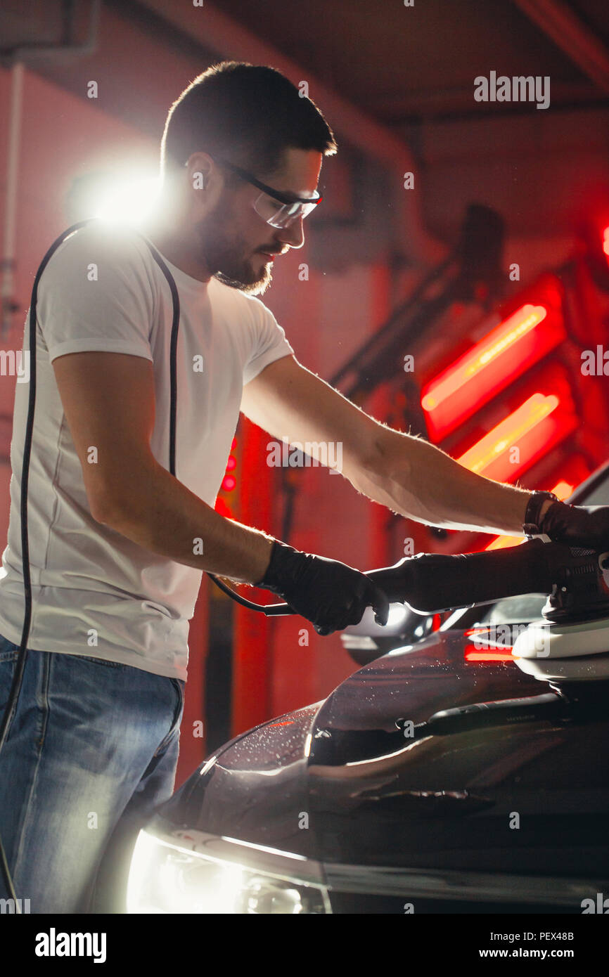 Dettagli auto - mani con lucidatrice orbitale nel negozio di riparazioni auto. Messa a fuoco selettiva. Foto Stock