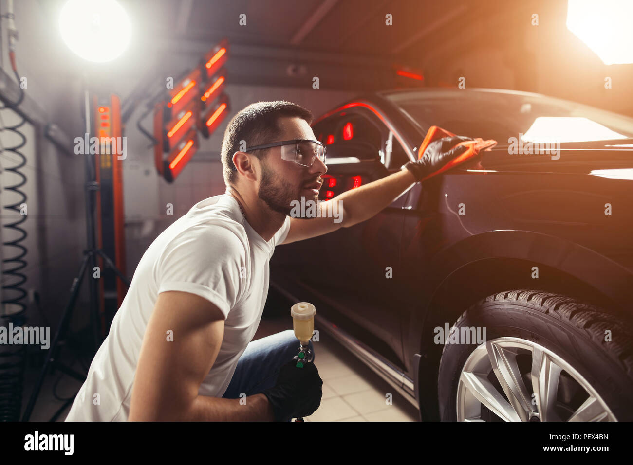 Un uomo che pulisce auto con panno in microfibra, auto che dettaglia o valeting concetto. Messa a fuoco selettiva. Foto Stock