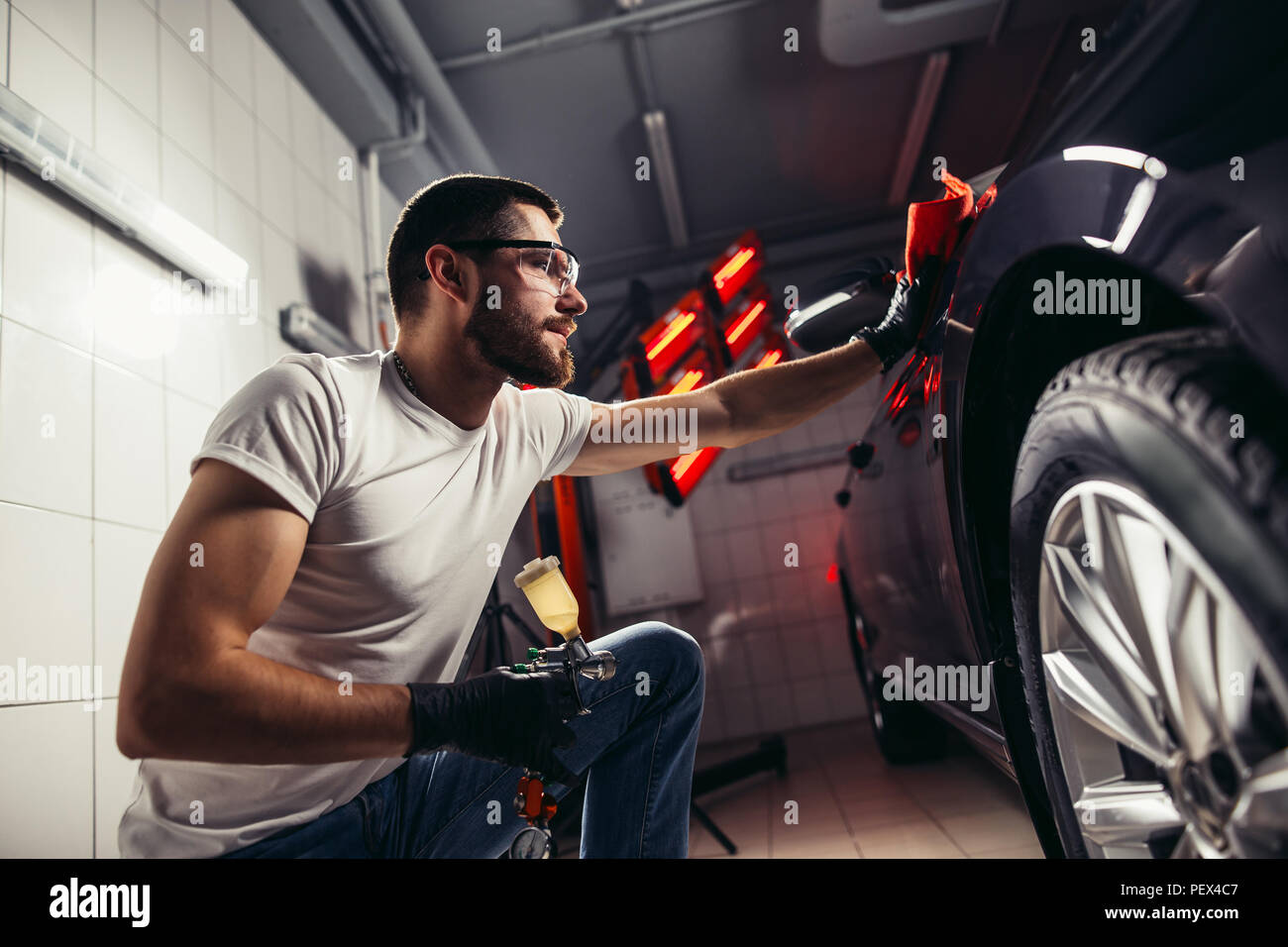 Un uomo che pulisce auto con panno in microfibra, auto che dettaglia o valeting concetto. Messa a fuoco selettiva. Foto Stock