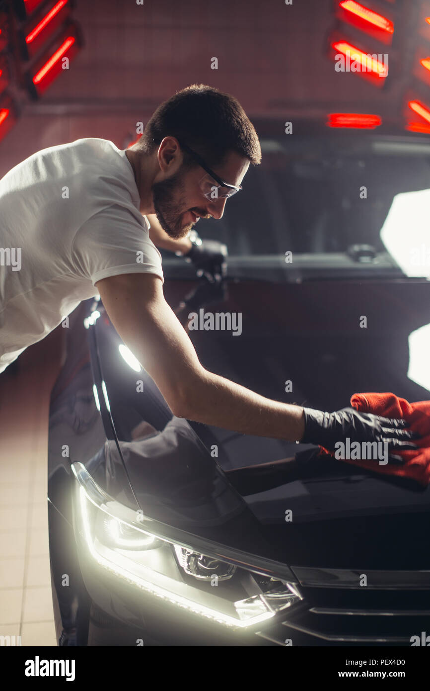 Dettagli auto - l'uomo detiene la microfibra in mano e leviga la vettura. Messa a fuoco selettiva. Foto Stock