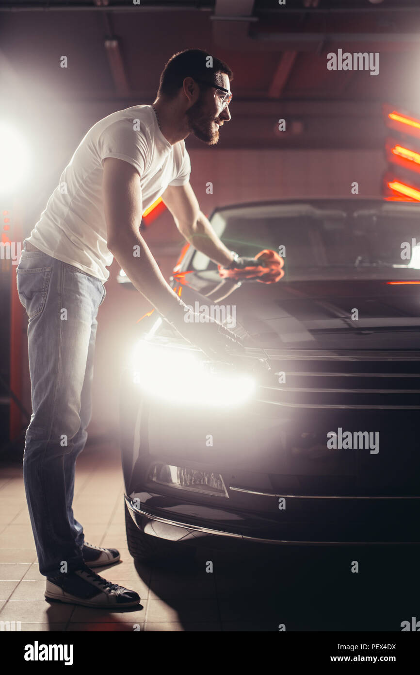 Dettagli auto - l'uomo detiene la microfibra in mano e leviga la vettura. Messa a fuoco selettiva. Foto Stock