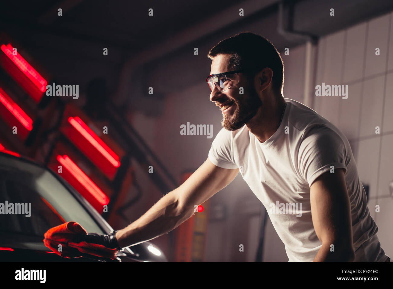 Un uomo che pulisce auto con panno in microfibra, auto che dettaglia o valeting concetto. Messa a fuoco selettiva. Foto Stock