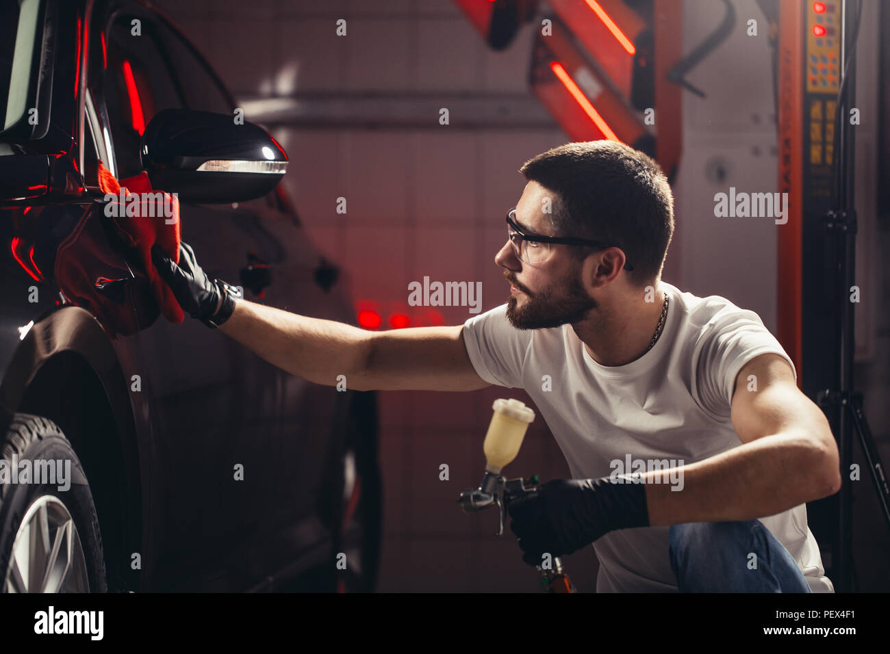 Un uomo che pulisce auto con panno in microfibra, auto che dettaglia o valeting concetto. Messa a fuoco selettiva. Foto Stock