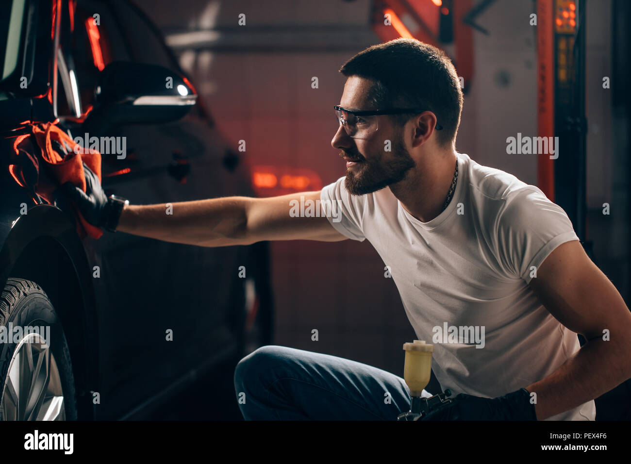 Un uomo che pulisce auto con panno in microfibra, auto che dettaglia o valeting concetto. Messa a fuoco selettiva. Foto Stock