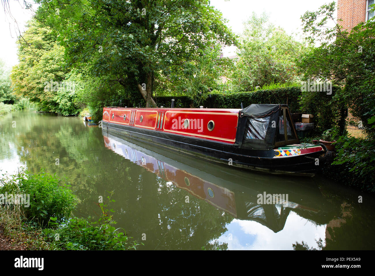 Red narrowboat ormeggiata presso il canal, Oxford Canal Foto Stock