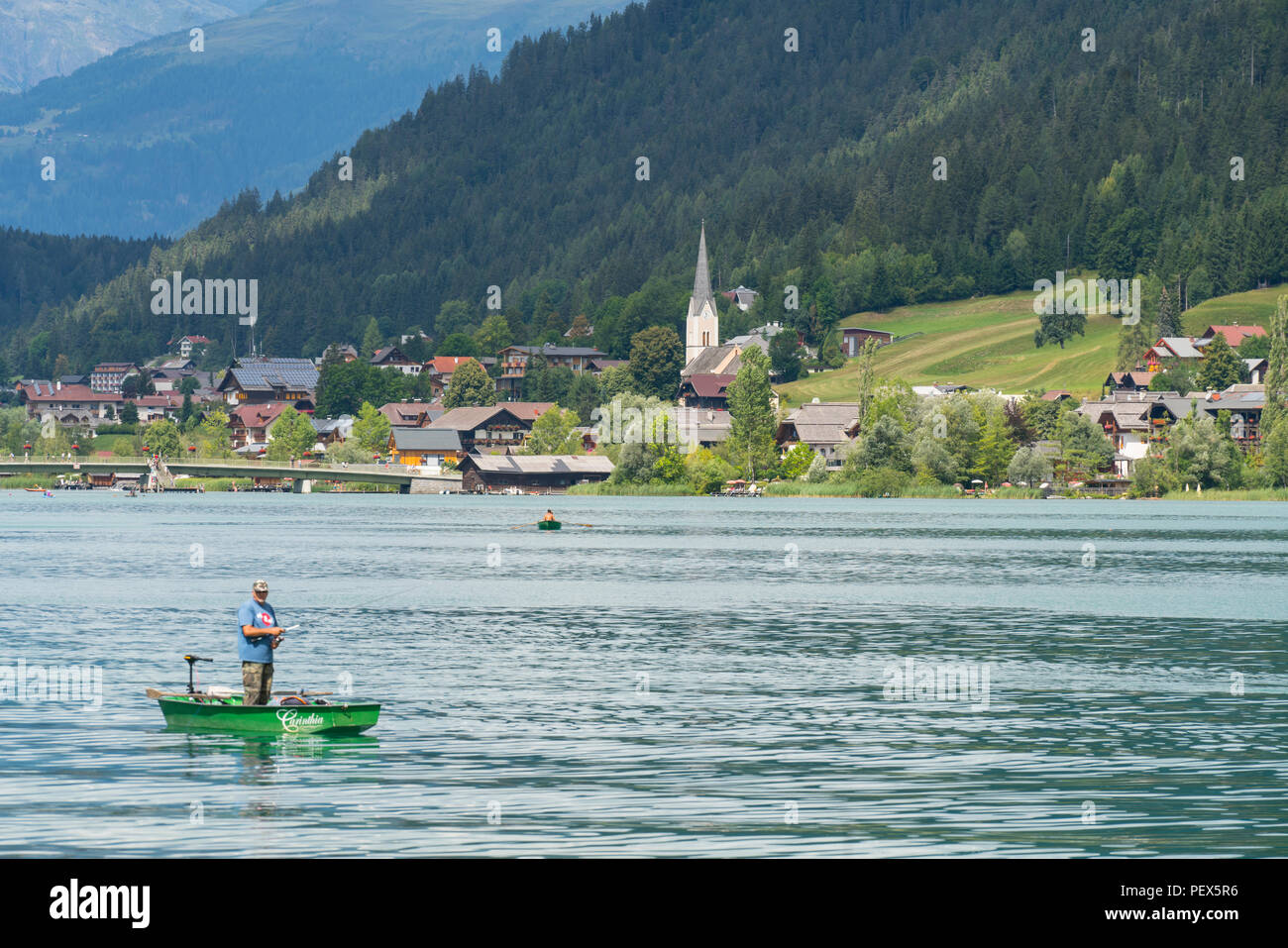 Un pescatore su una piccola barca nel lago Weissensee, Austria Foto Stock
