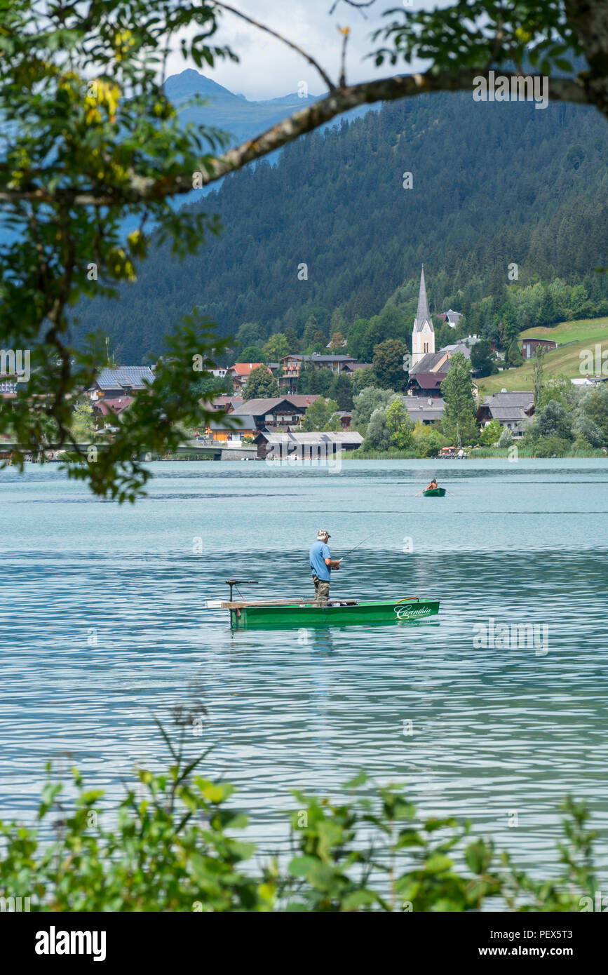 Un pescatore su una piccola barca nel lago Weissensee, Austria Foto Stock