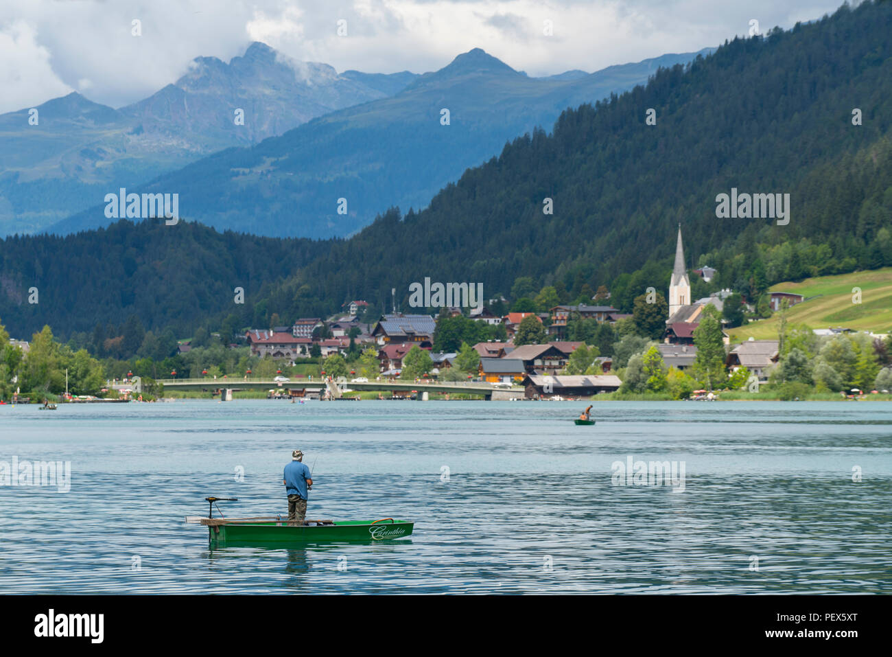 Un pescatore su una piccola barca nel lago Weissensee, Austria Foto Stock