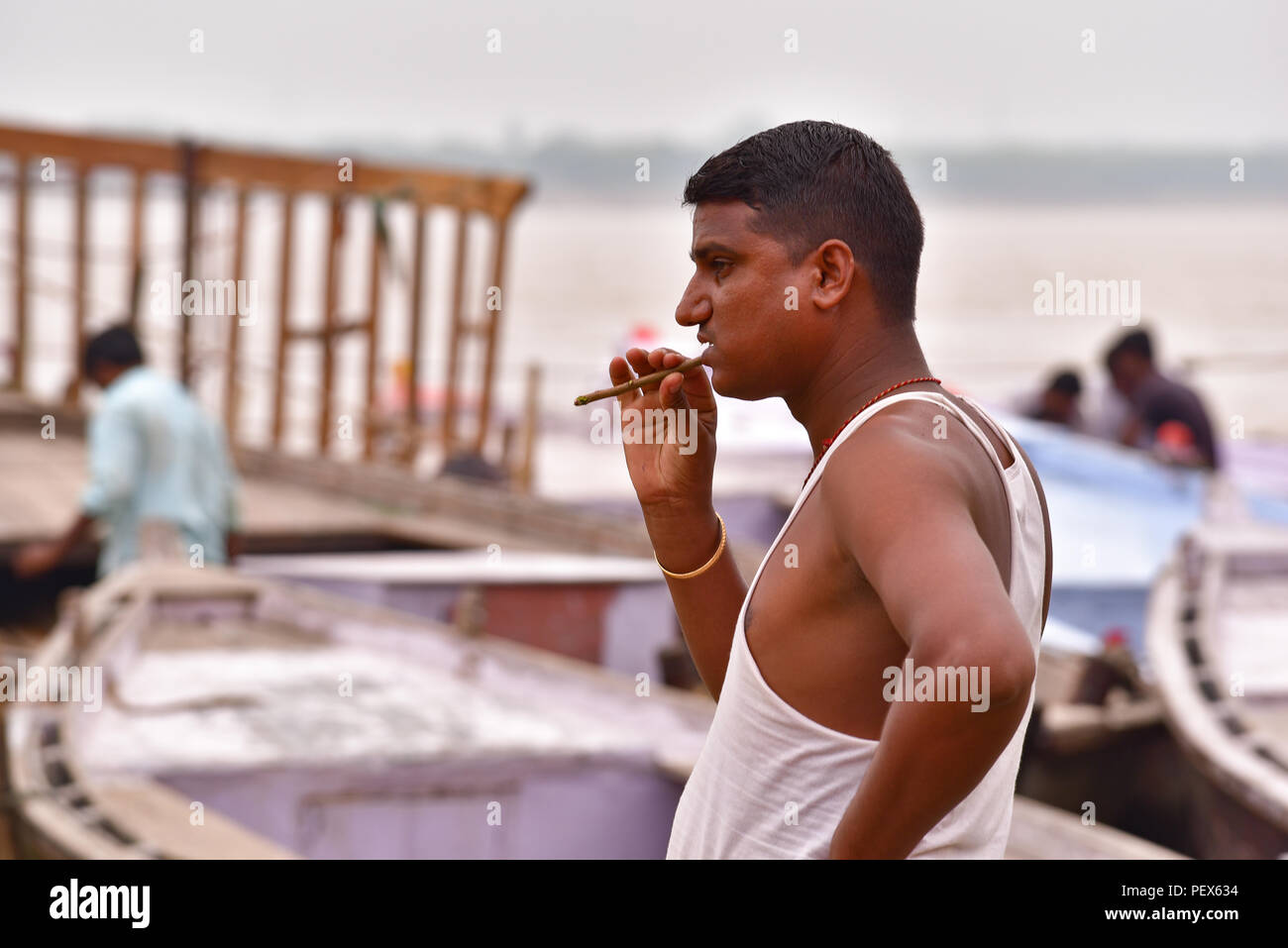 L'uomo spazzolare i denti al fiume Gange Foto Stock