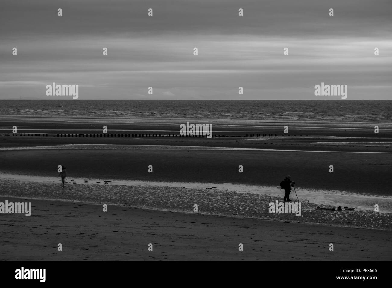 Una immagine in bianco e nero di un fotografo di scattare le foto sulla spiaggia Foto Stock